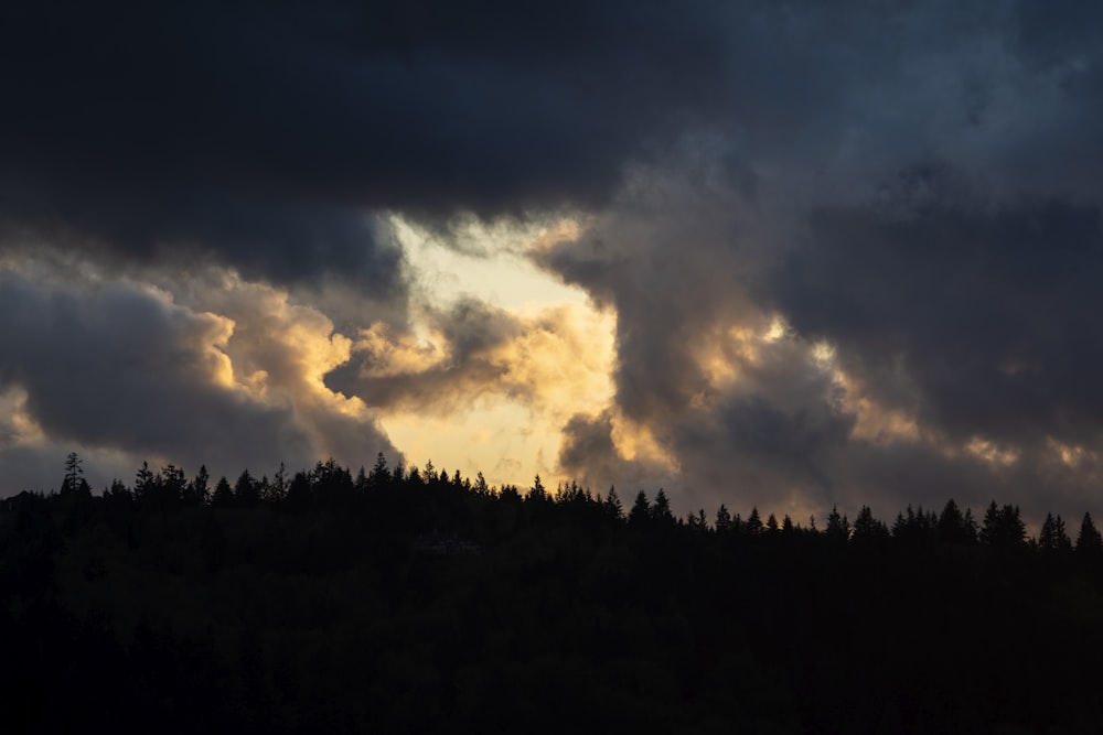 the sun is shining through the clouds over the trees