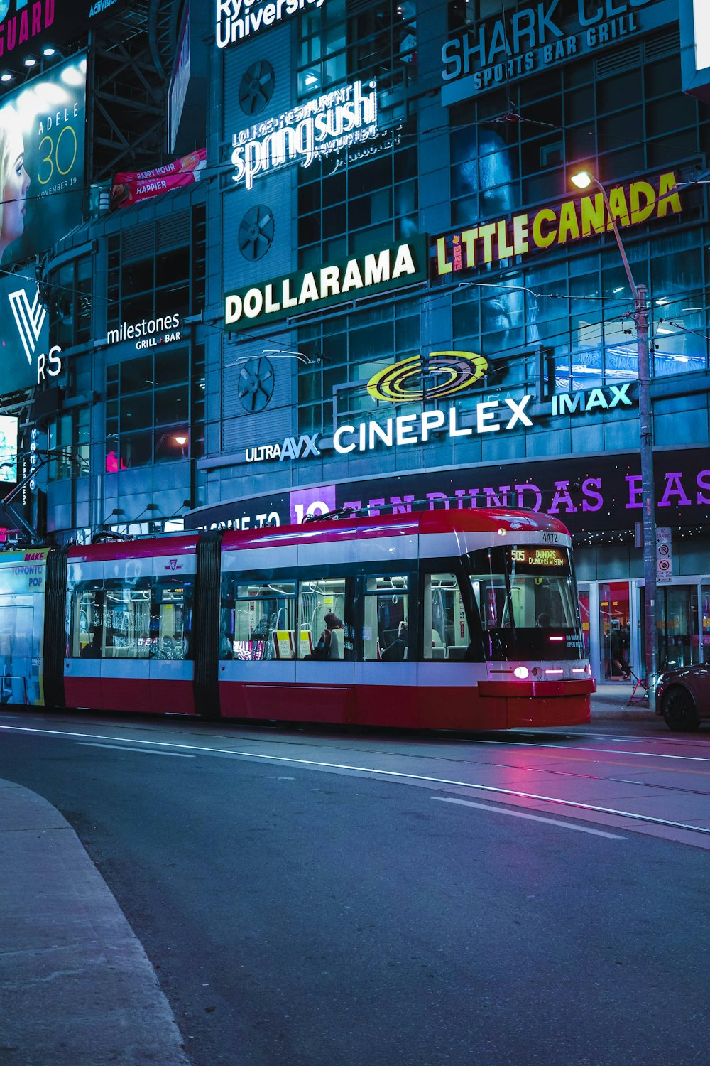 a red and white train on a city street