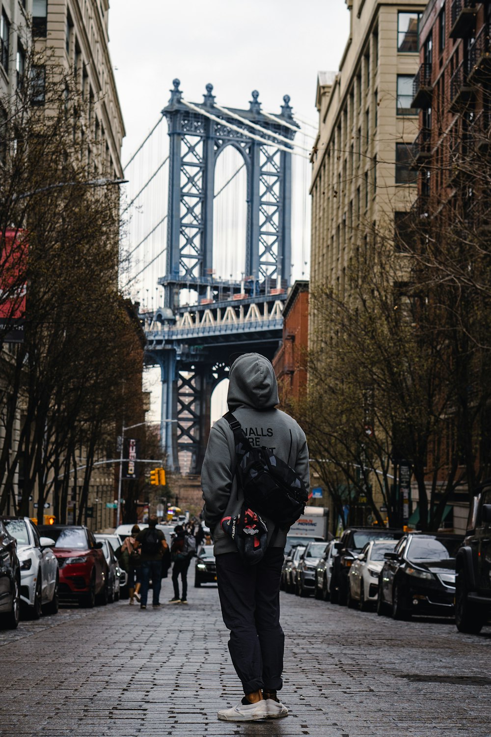 a person walking down a street with a bridge in the background