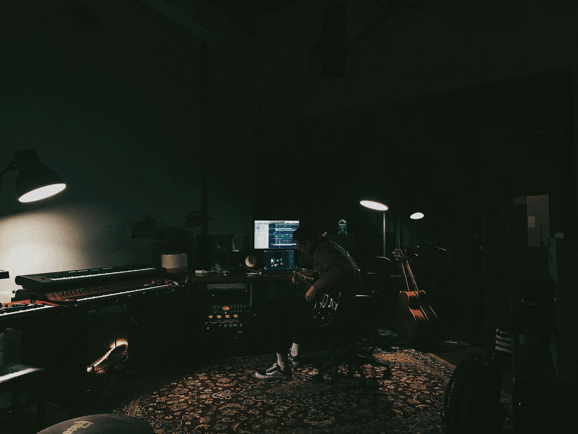 a person sitting in a dark room with a guitar