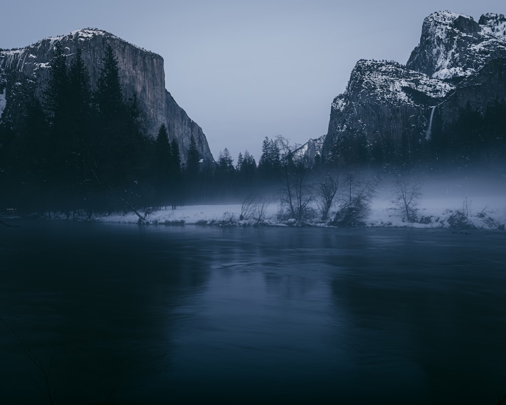 a mountain covered in snow next to a body of water