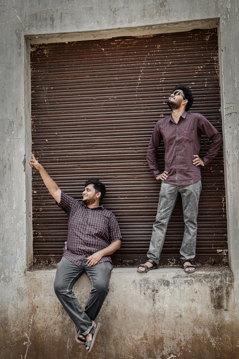 two men standing next to each other in front of a garage door