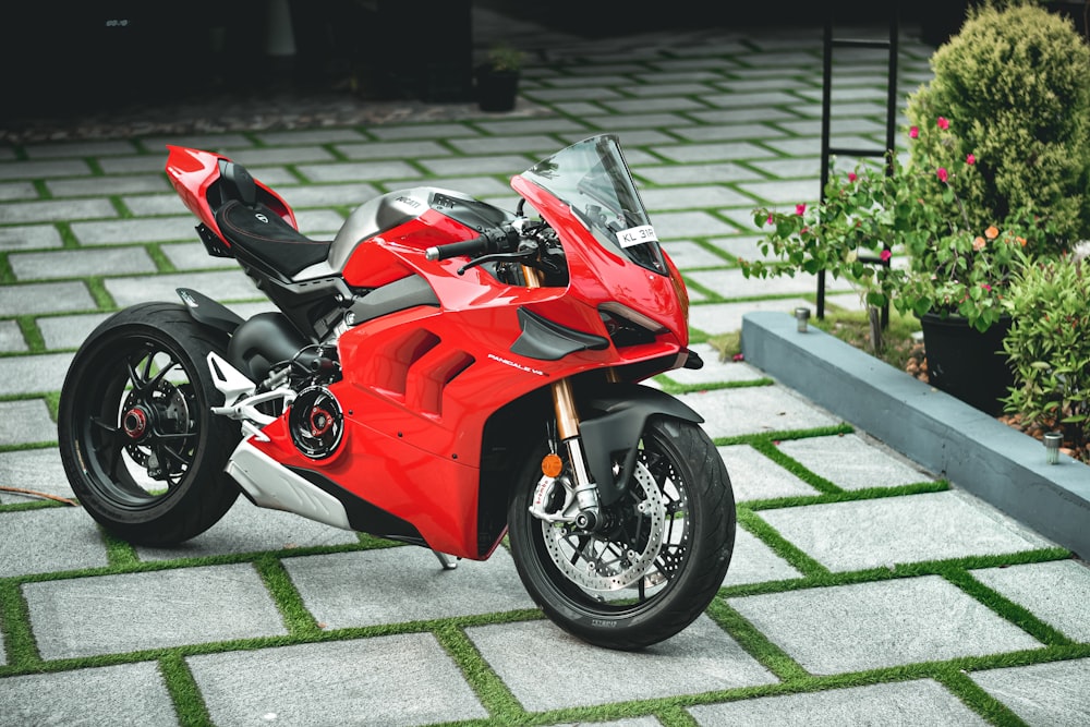 a red motorcycle parked on top of a sidewalk