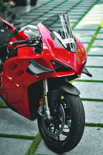 A sleek red sport motorcycle parked on a winding mountain road at sunset.