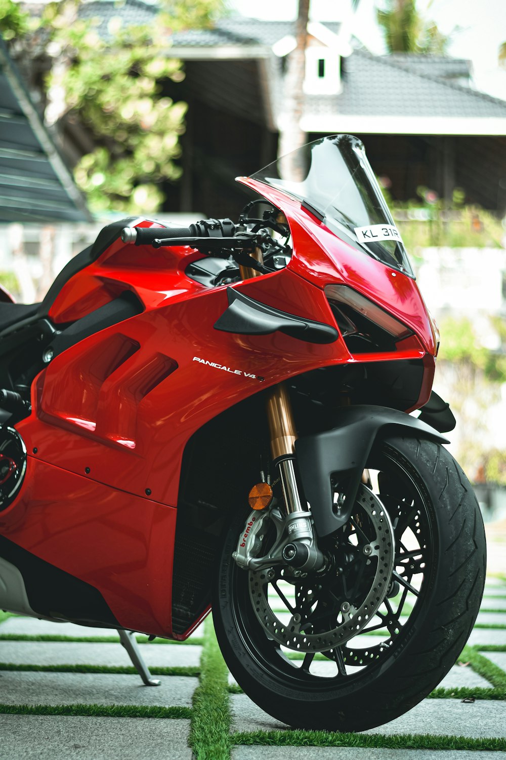 a red motorcycle parked in a driveway next to a house