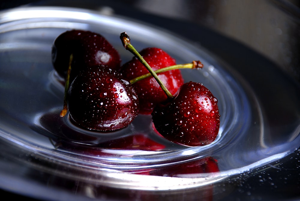 three cherries in a bowl of water on a table