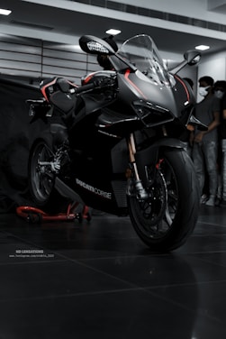 a black motorcycle parked in a garage next to a group of people