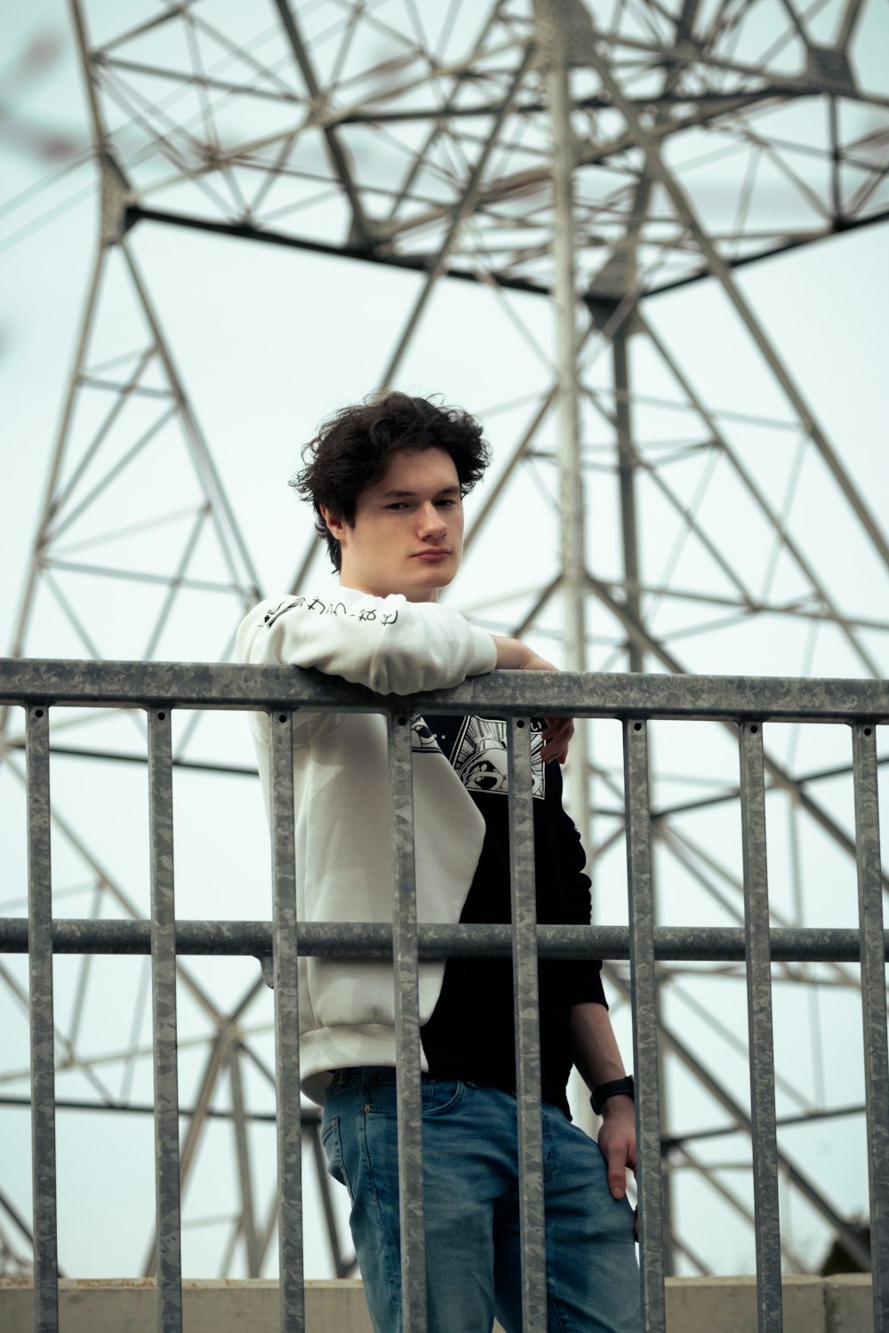 a young man leaning on a metal fence