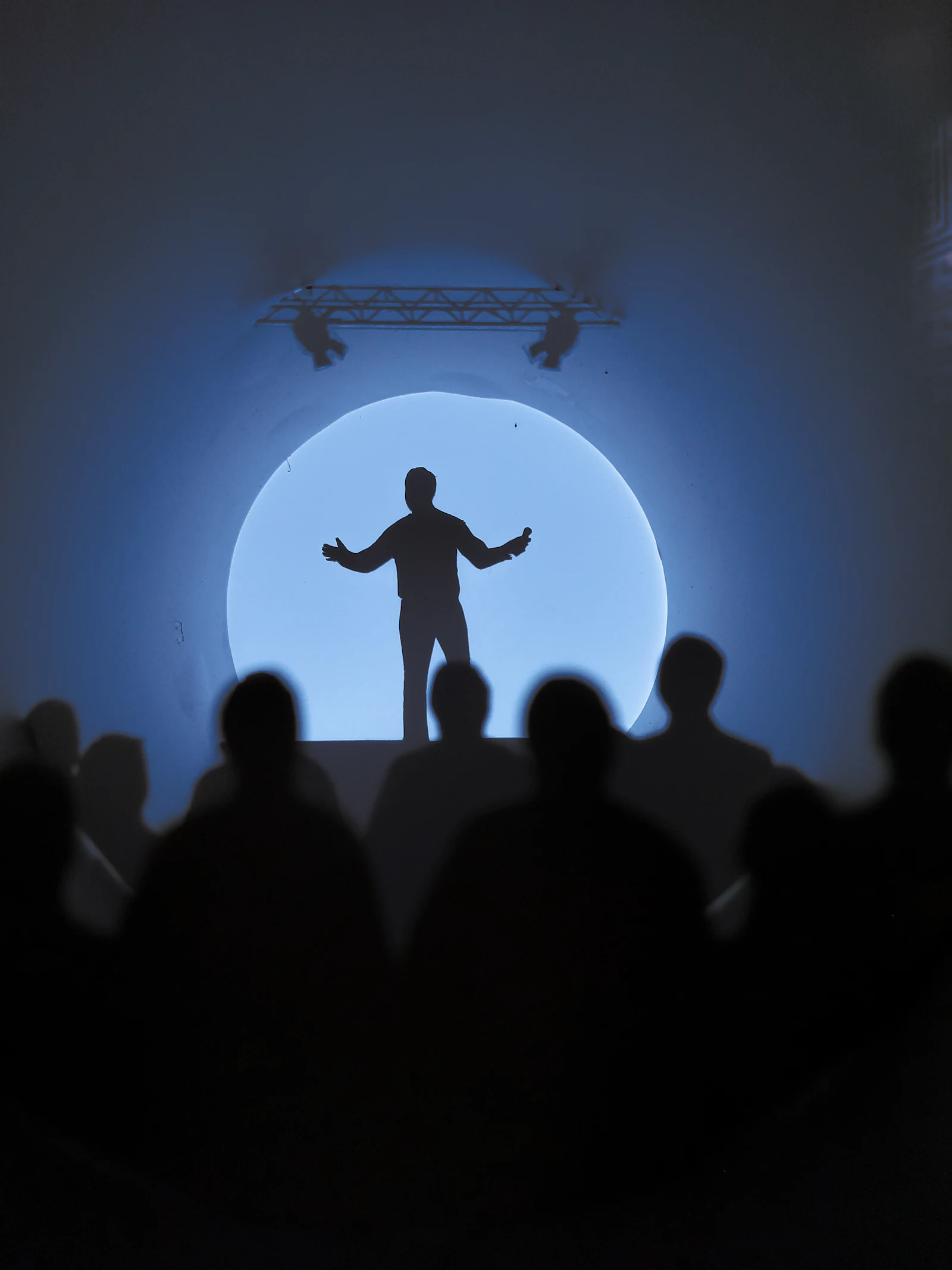 A speaker standing inside a circle of light
