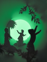 Silhouettes of three figures dancing against a glowing green background, surrounded by foliage and a large circular light source resembling a moon.