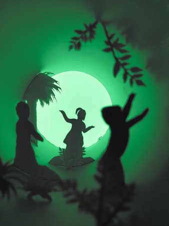 Silhouettes of three figures dancing against a glowing green background, surrounded by foliage and a large circular light source resembling a moon.