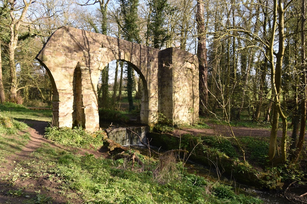 an old stone bridge in the middle of a forest