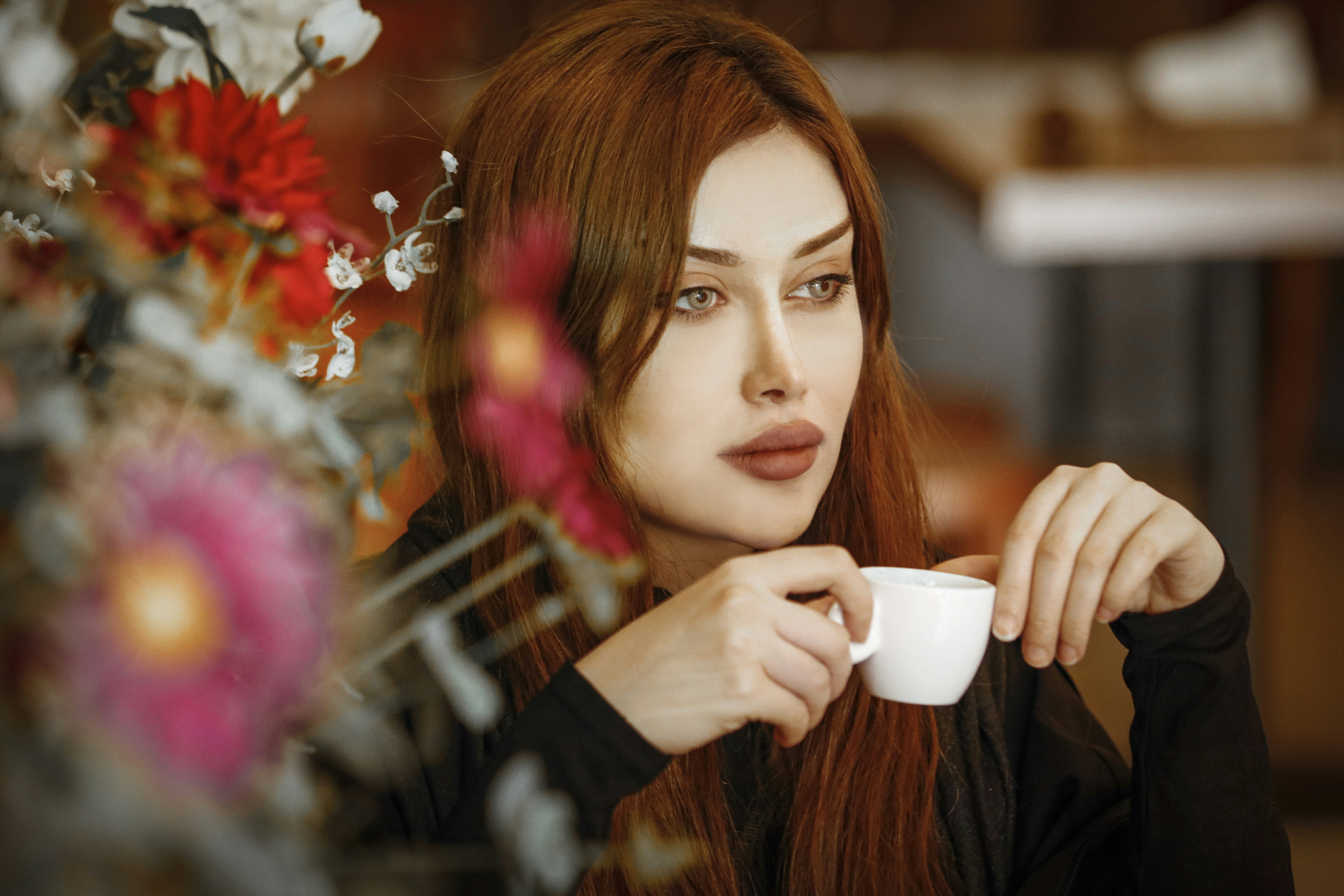 a woman with red hair holding a cup of coffee