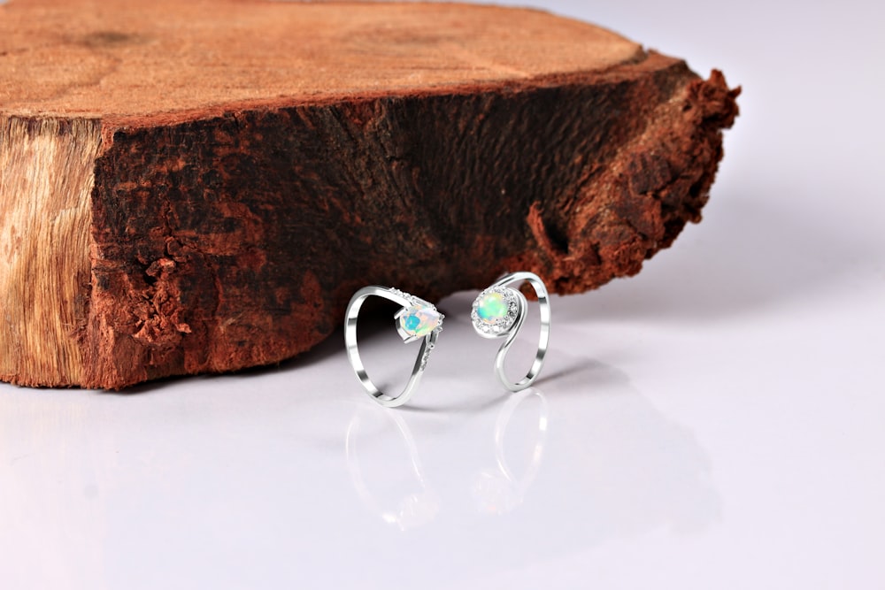 a pair of white opal earrings sitting on top of a piece of wood