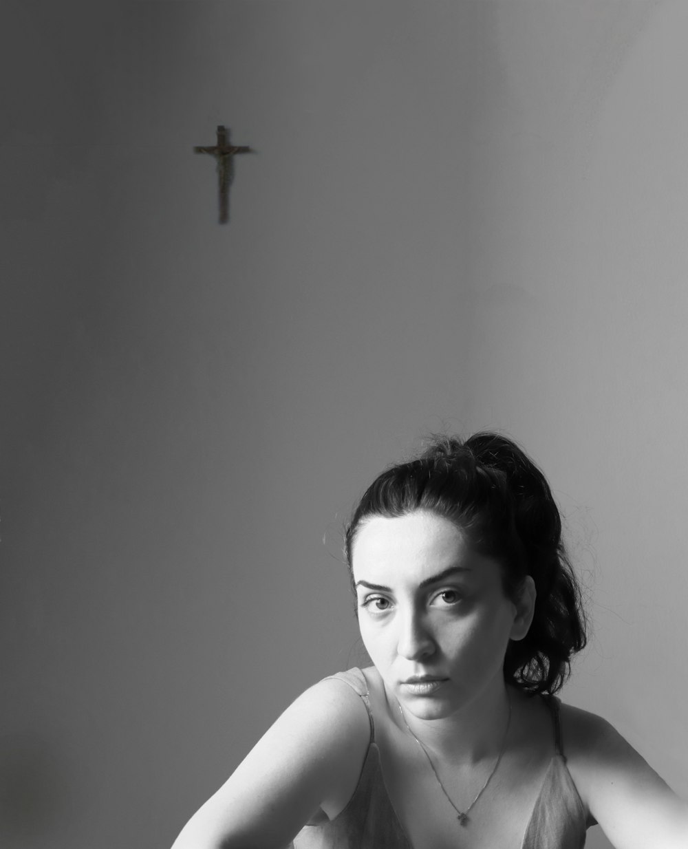 a black and white photo of a woman with a cross in the background