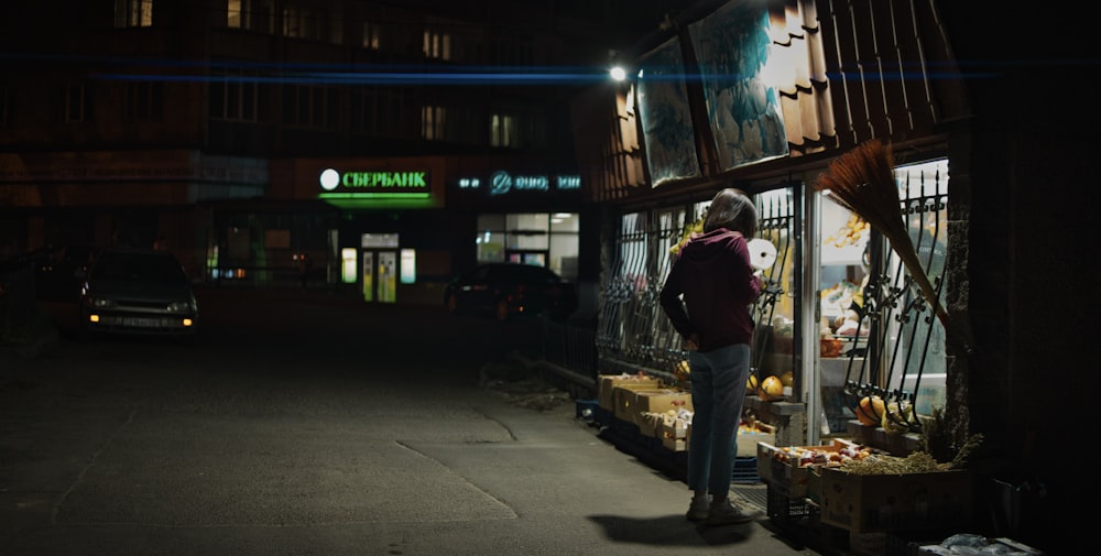 a man standing in front of a store at night