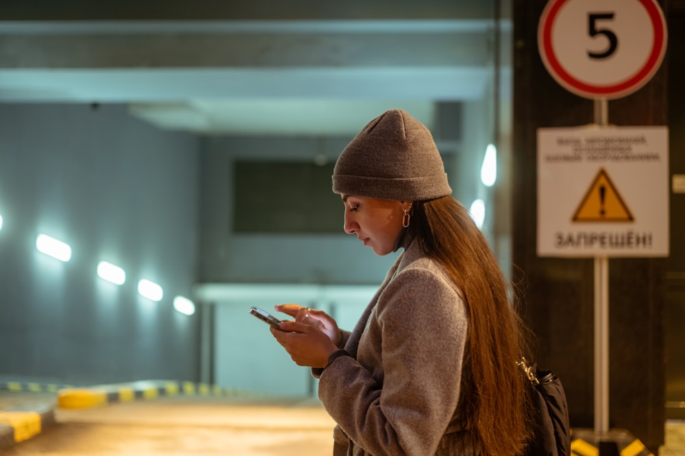 a woman standing in a parking garage looking at her cell phone