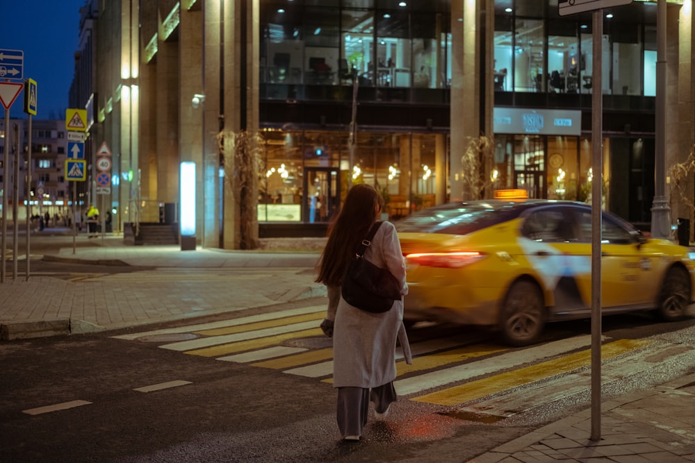 a woman walking across a street at night