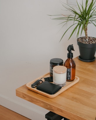 a wooden table topped with a bottle of liquid and a potted plant