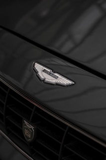 Detail of a polished car emblem reflecting soft beige and grey tones.