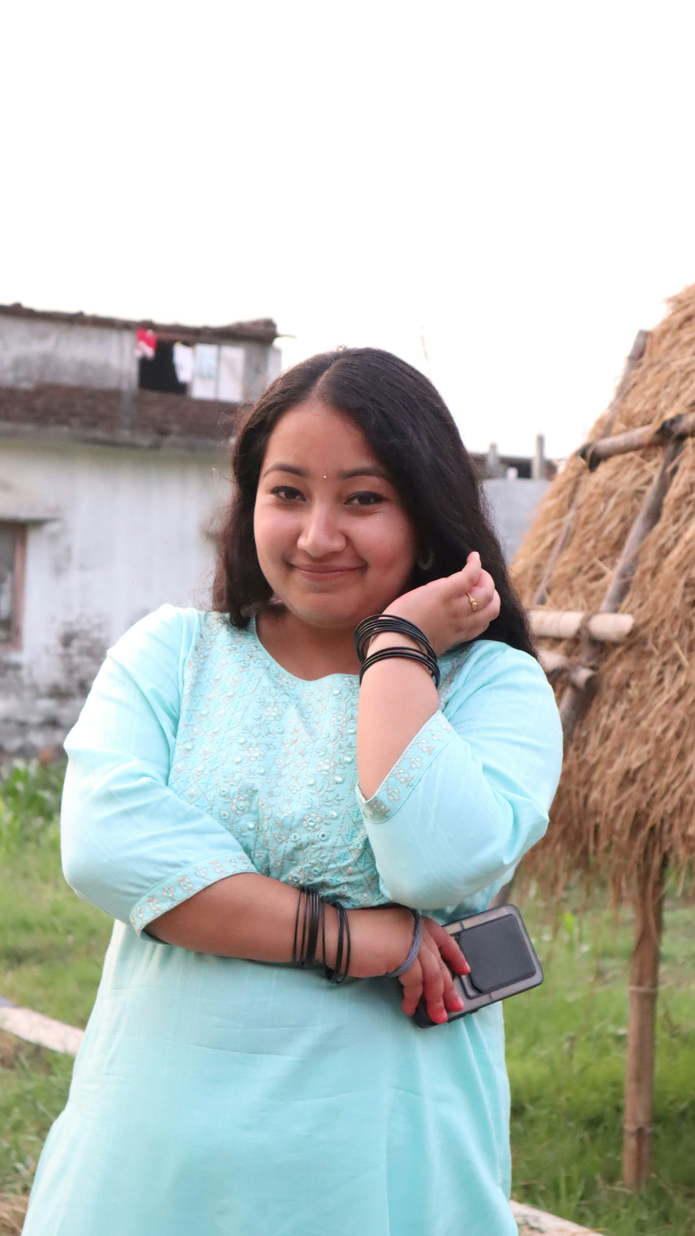 a woman standing in front of a straw hut