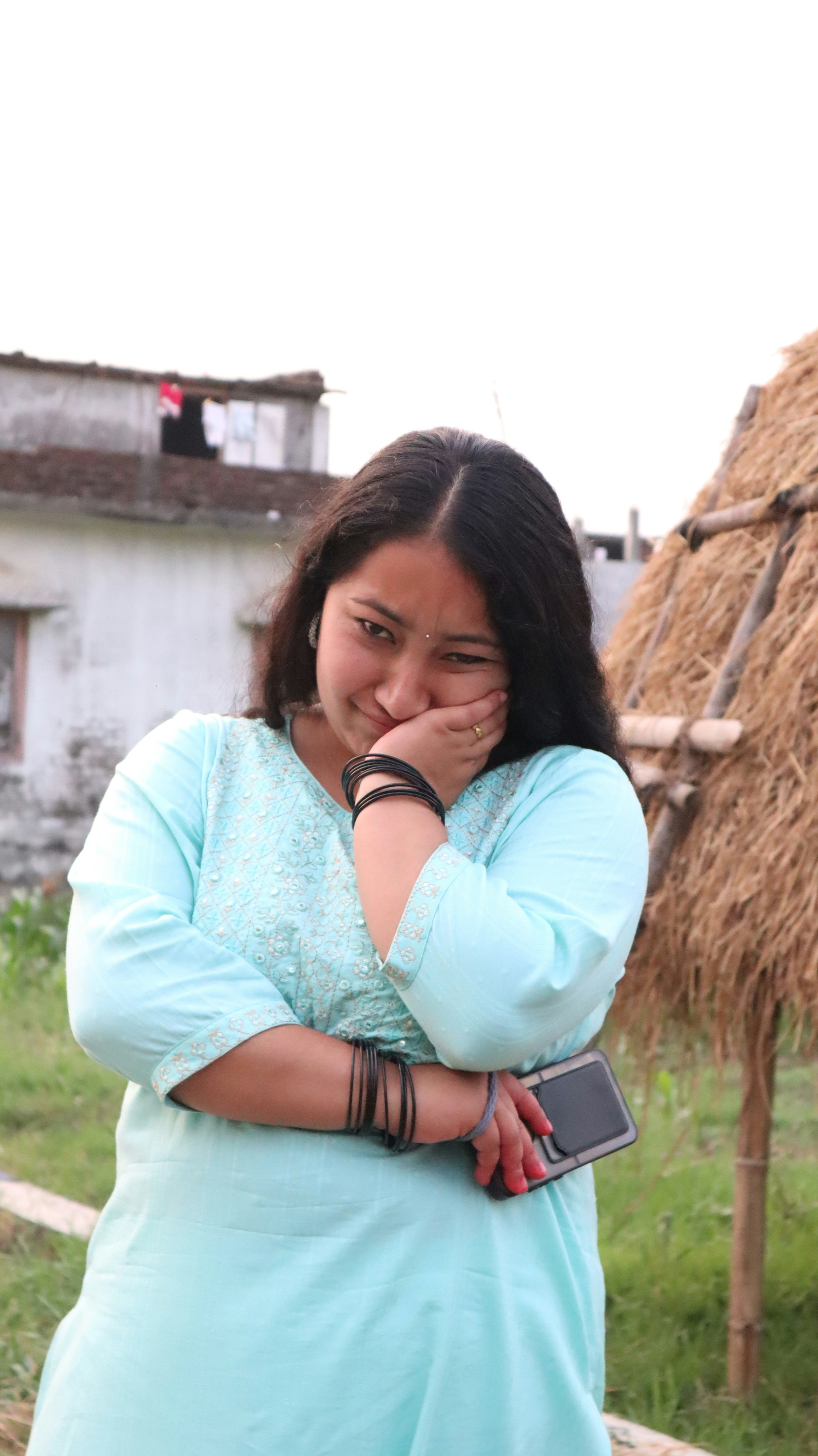 a woman standing in front of a straw hut