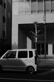 A compact car parked by a city street on a sunny day.