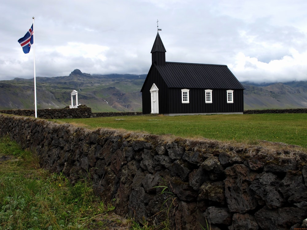 a small black church with a flag on top of it