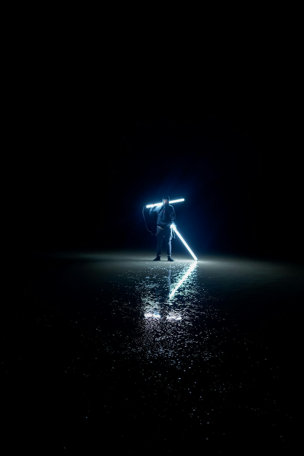 a man standing in the dark holding a light saber