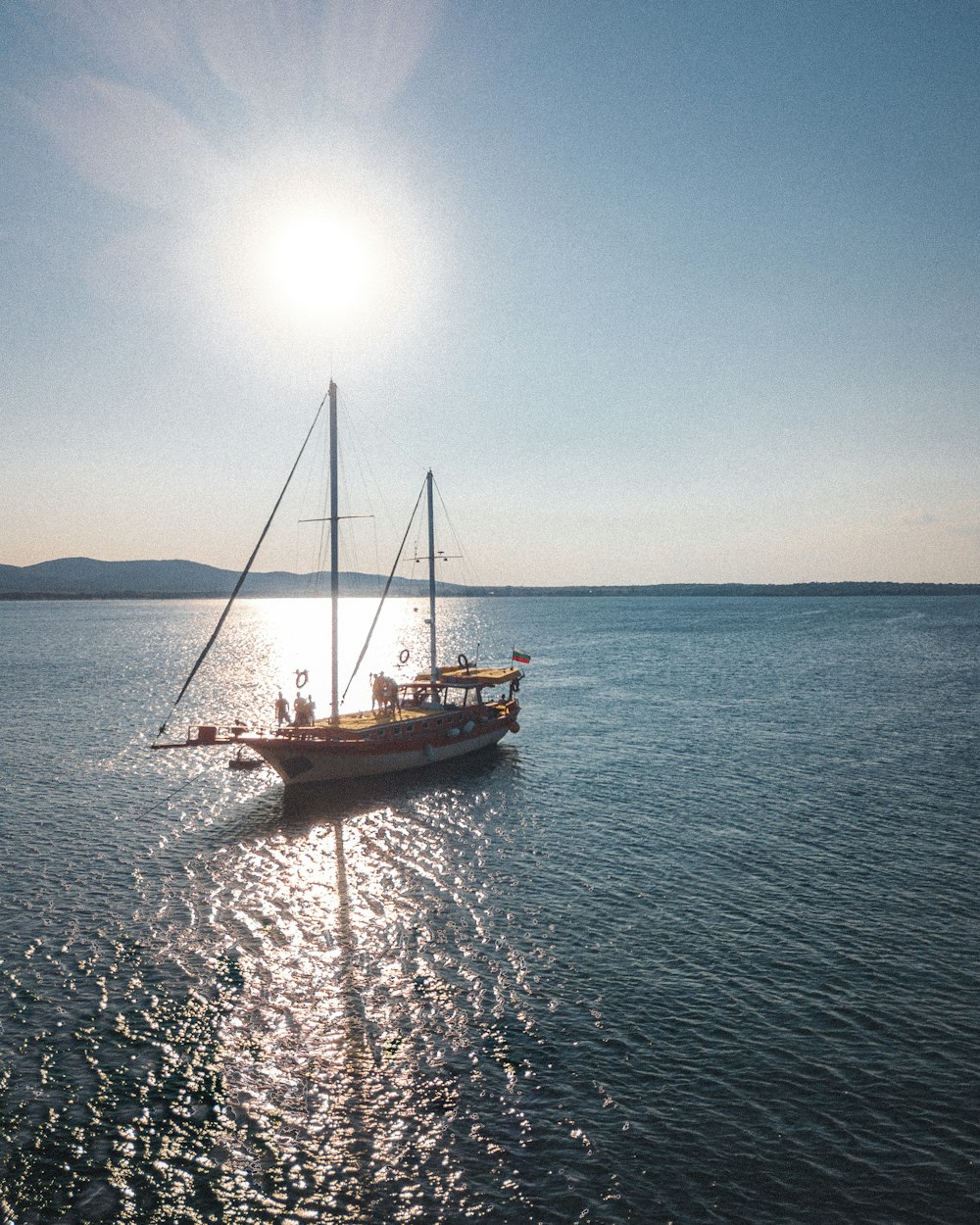 a sailboat in the middle of the ocean on a sunny day