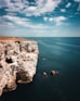 a person standing on top of a cliff next to the ocean