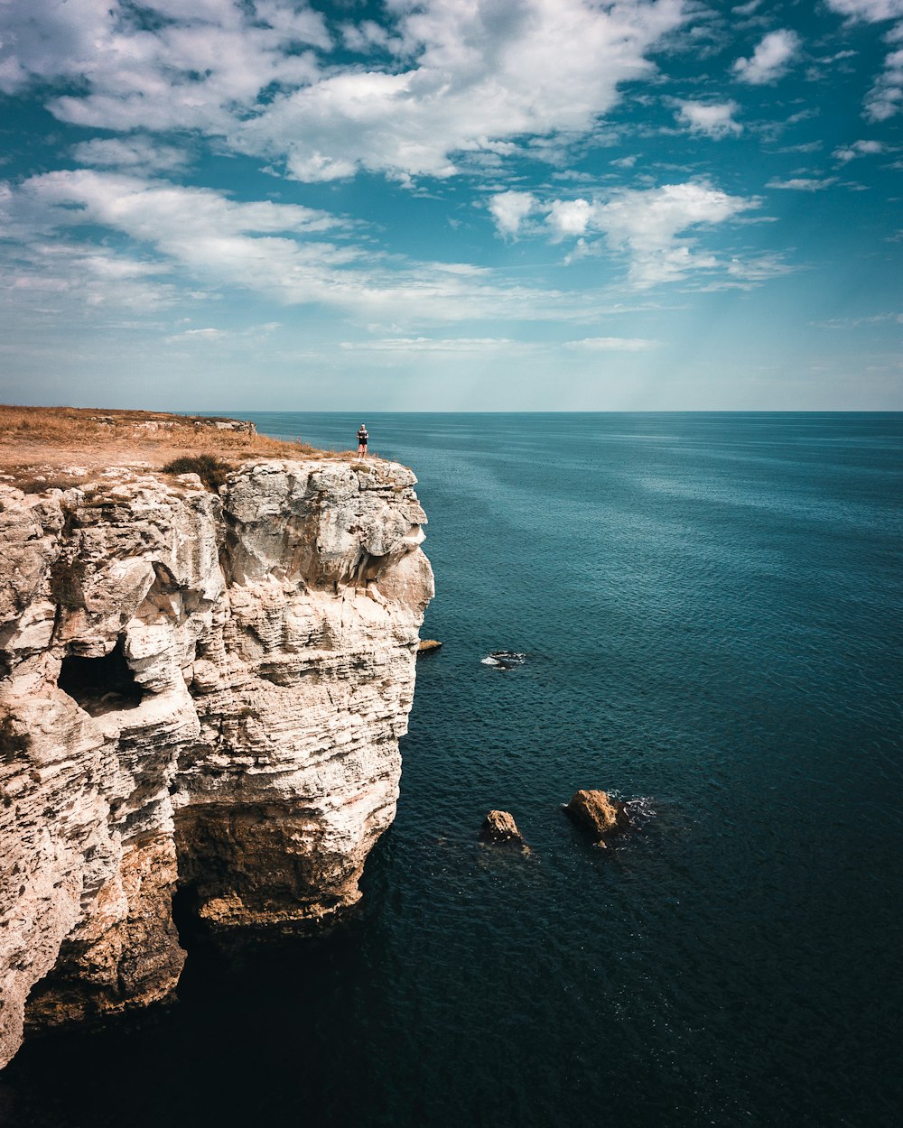 a person standing on top of a cliff next to the ocean