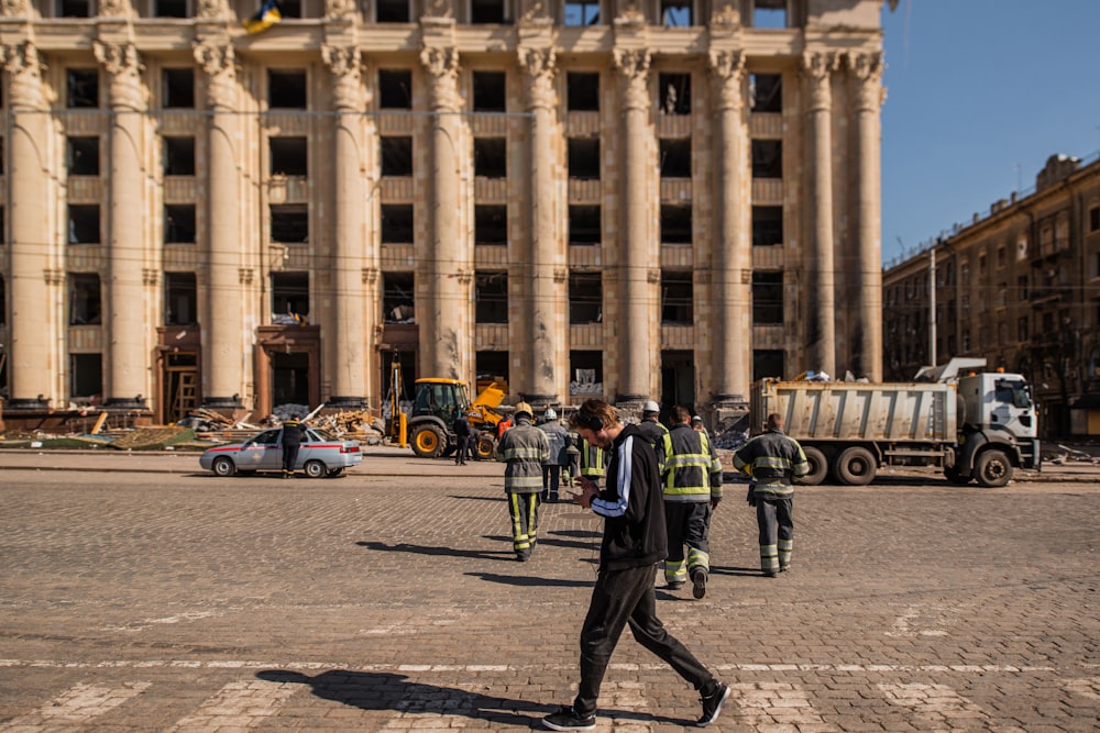 a group of men walking across a street next to a tall building