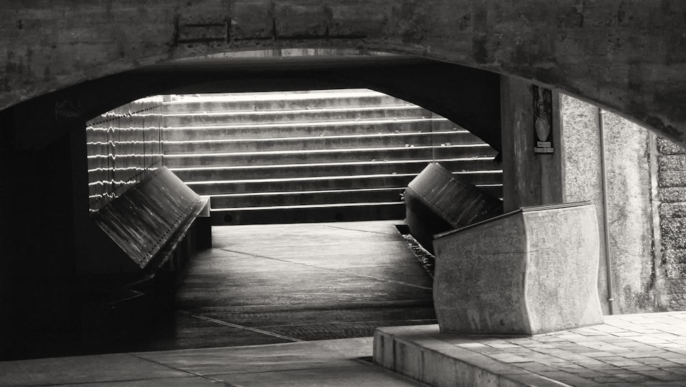 a black and white photo of a bench in a tunnel