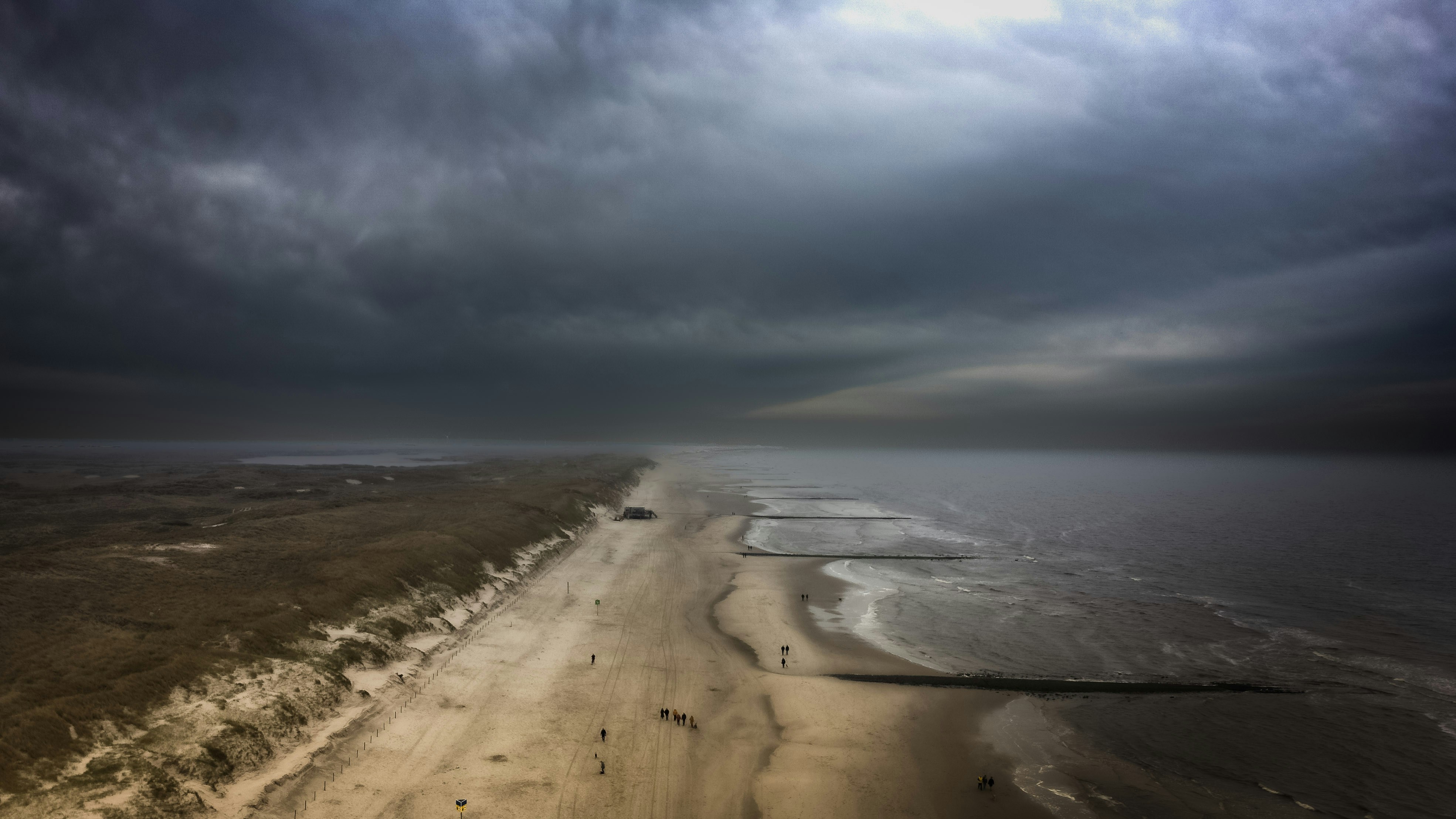 an aerial view of a beach and ocean under a cloudy sky