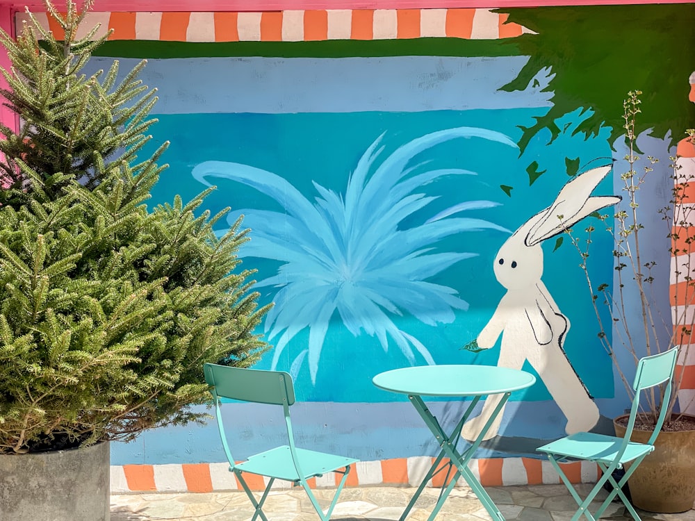 a painting of a rabbit on a wall next to a table and chairs