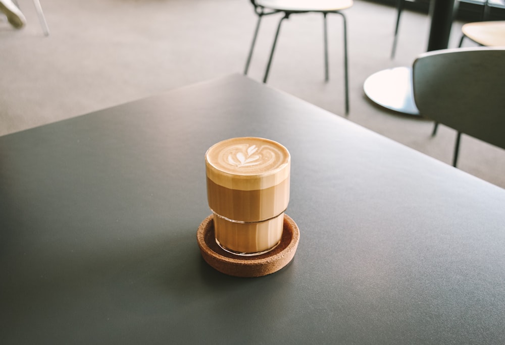 a cup of coffee sitting on top of a wooden coaster