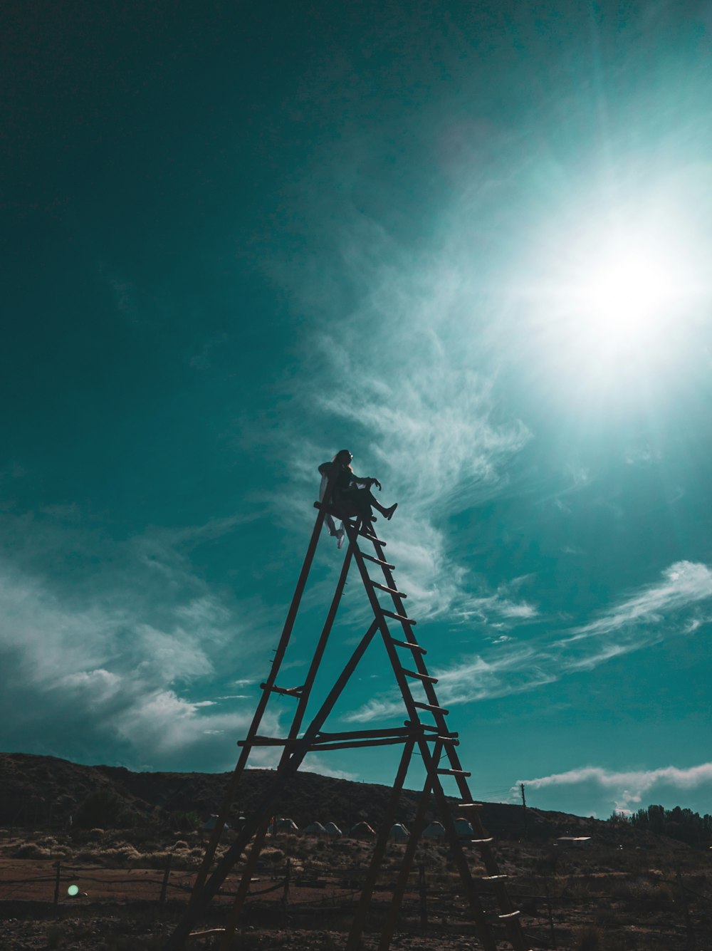 a man on a ladder reaching up into the sky