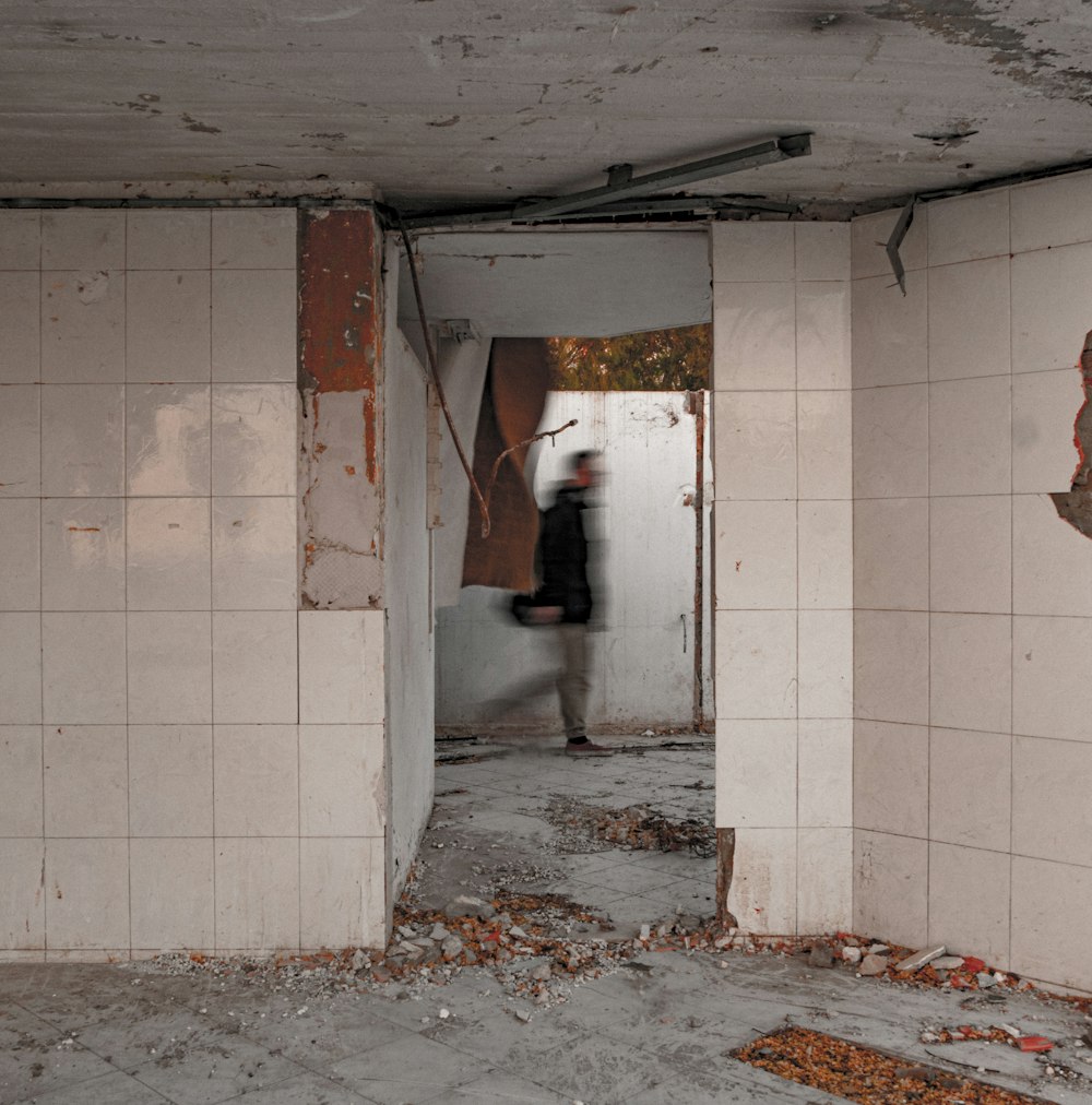 a person standing in a room with white tiles