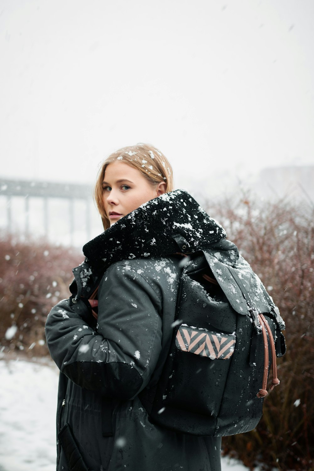 a woman standing in the snow with her back to the camera