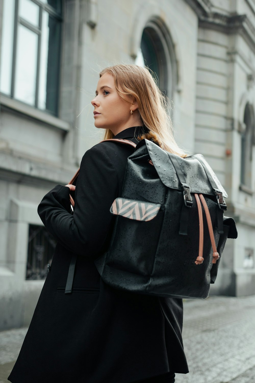 a woman in a black coat carrying a black backpack