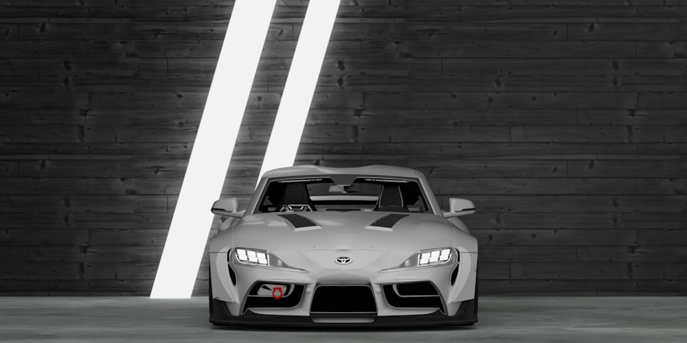 a gray sports car parked in front of a wooden wall