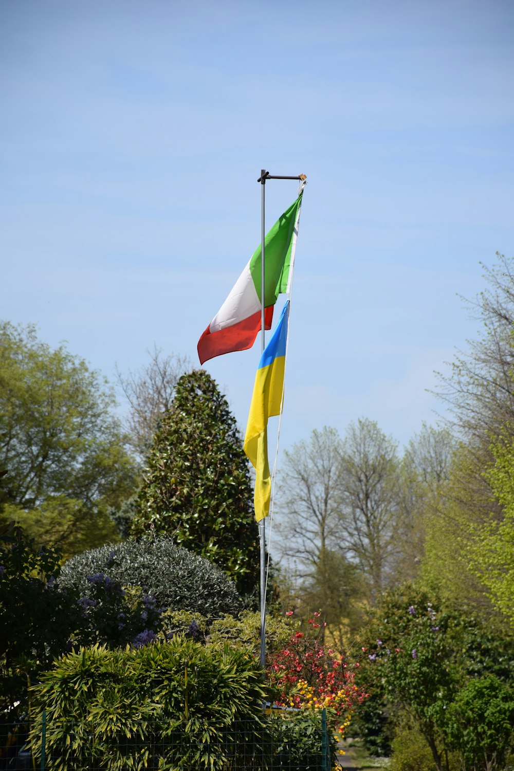 two flags flying in the wind in a park