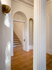 Elegant before-and-after shot of a remodeled home entryway with new flooring and lighting.