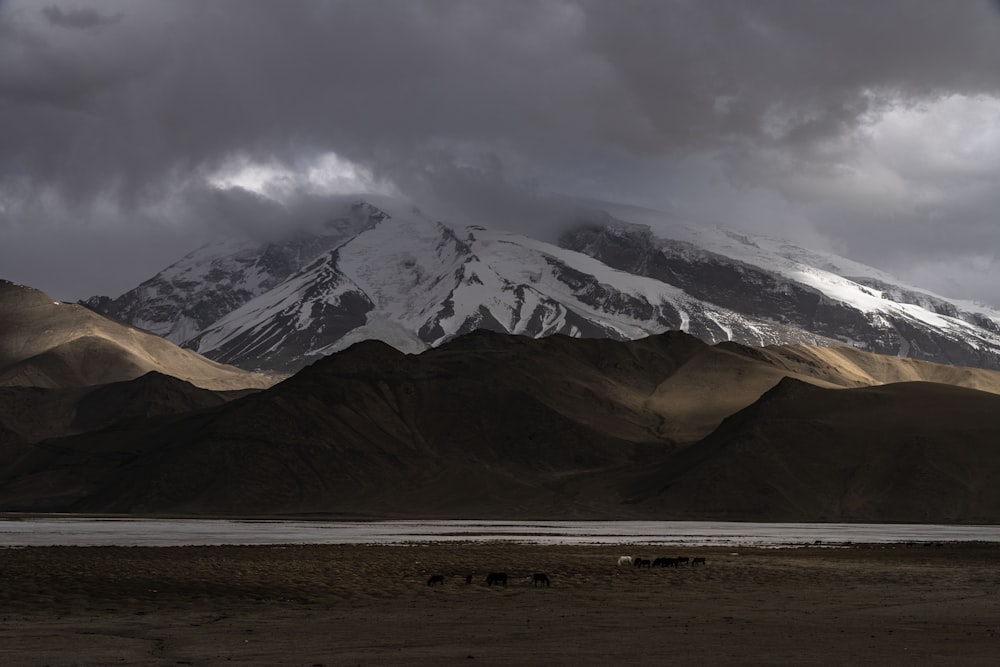 a large mountain covered in snow under a cloudy sky