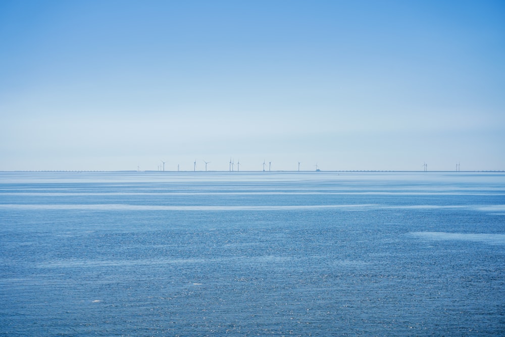 a large body of water with wind mills in the distance