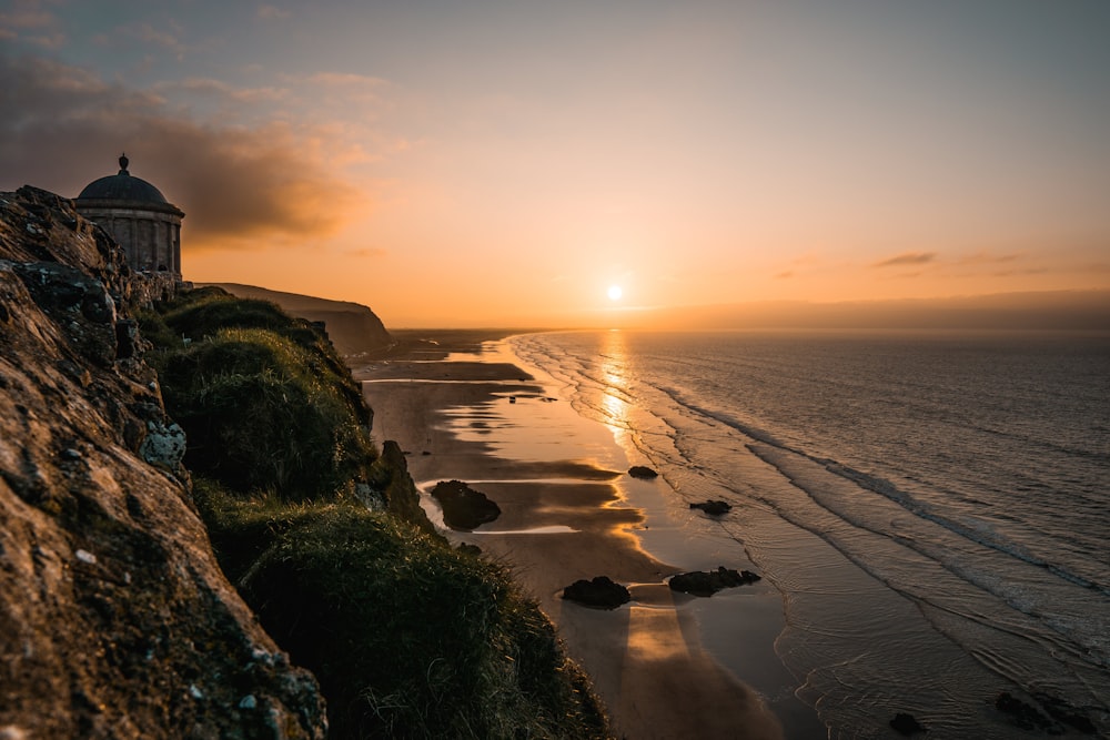 the sun is setting over the ocean and the beach