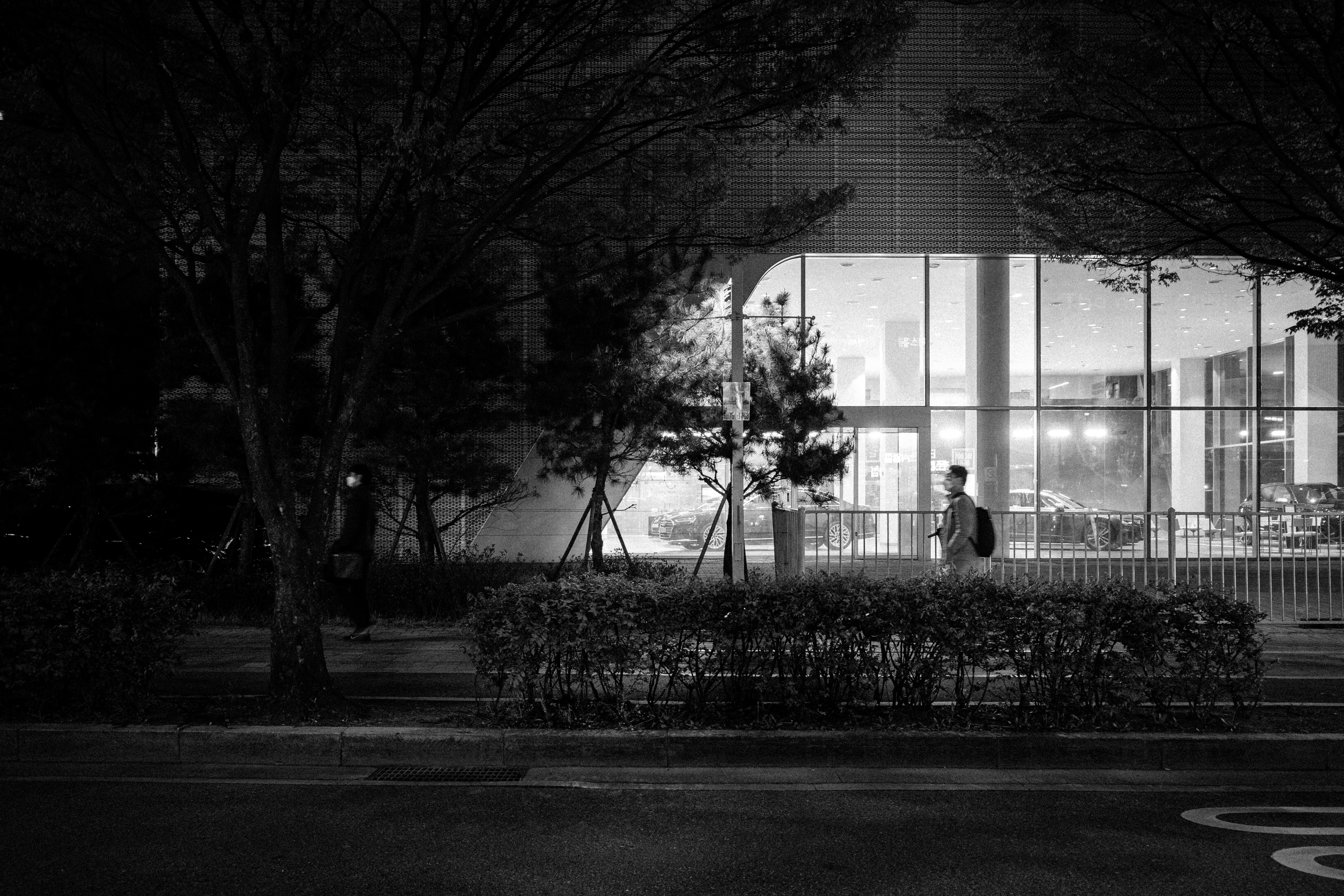 a black and white photo of a person walking in front of a building
