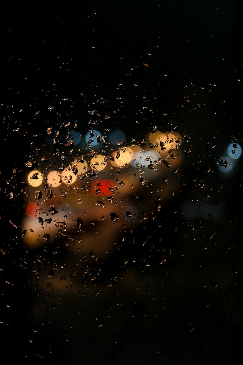 rain drops on a window with a blurry car in the background
