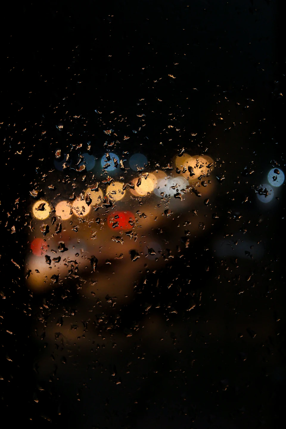 Close-up view through a window with blurred raindrops resembling a starry night sky effect